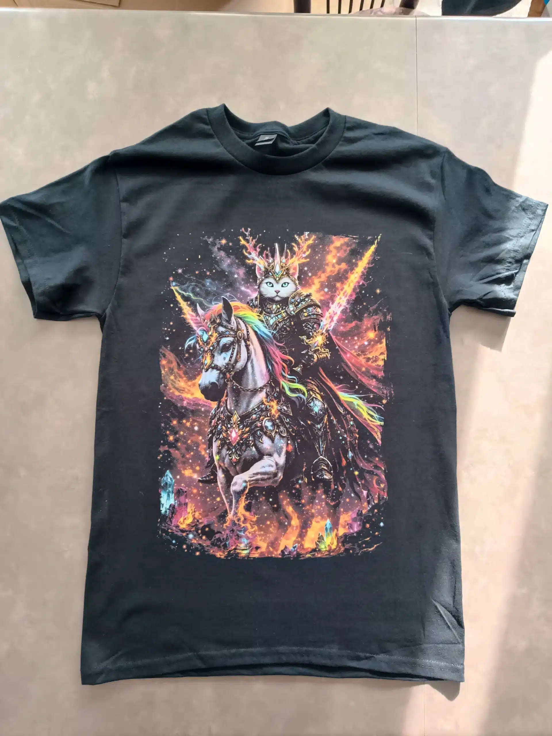 T-shirt noir avec une impression DTF multicolore représentant un chat en armure sur un cheval.
